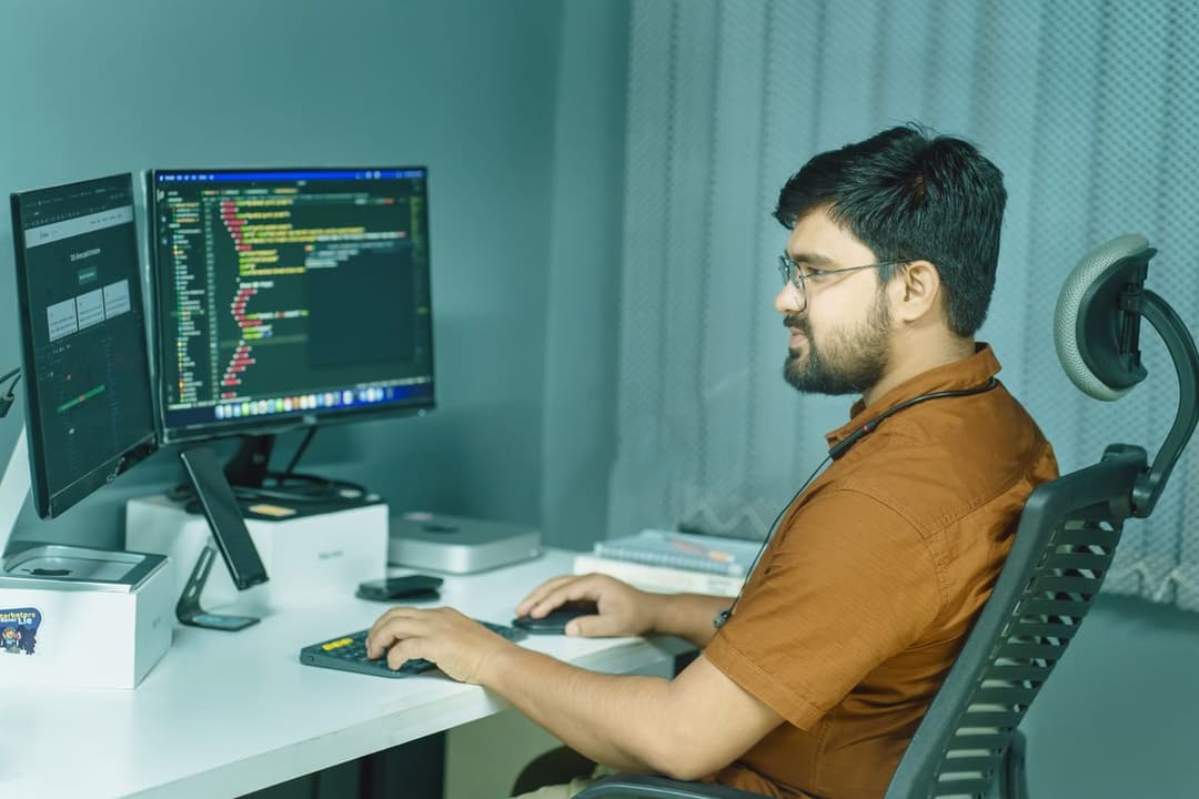 A developer writing code across two monitors in an office