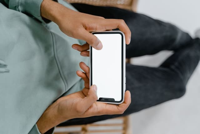 Hands holding a smartphone with a blank screen
