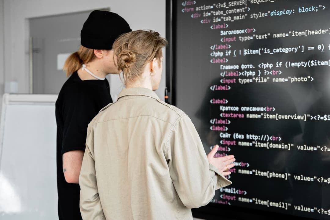 Two developers reviewing code on a large screen