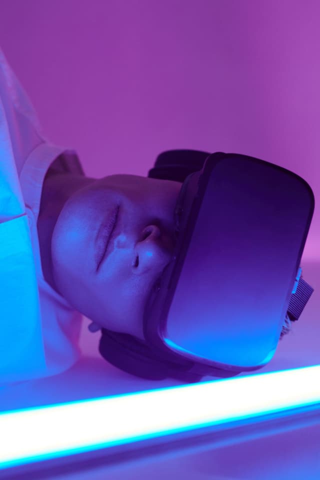 A person wearing a VR headset under blue and purple light