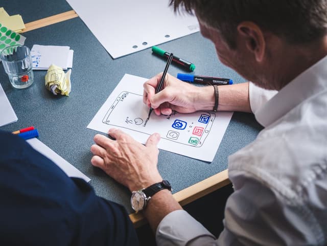 A designer sketching a mobile app prototype on paper