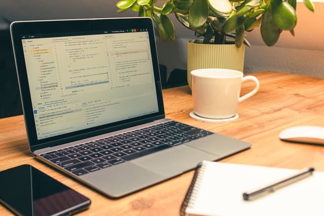A laptop with a code editor open beside a cup of coffee