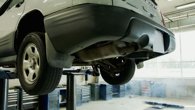 A vehicle raised on a lift in an auto repair shop