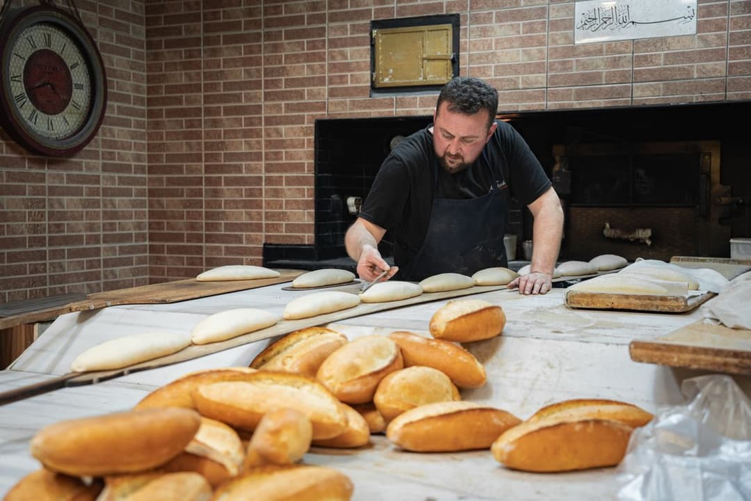 A baker shaping fresh bread dough by hand