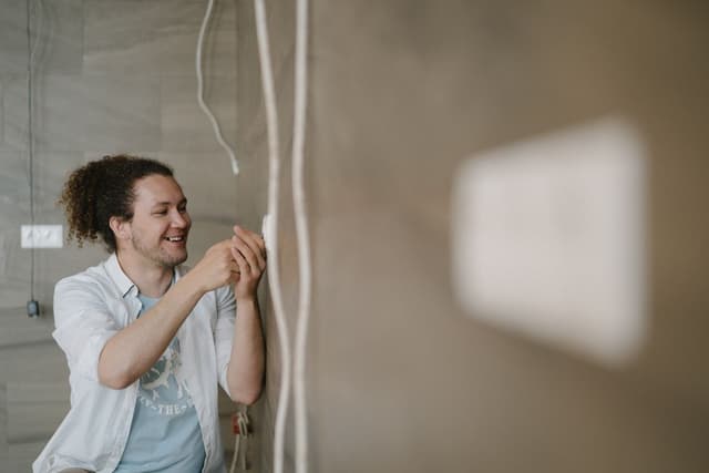 An electrician adjusting a wall outlet