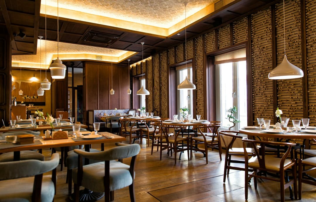 An elegant restaurant dining room set with tables and pendant lighting